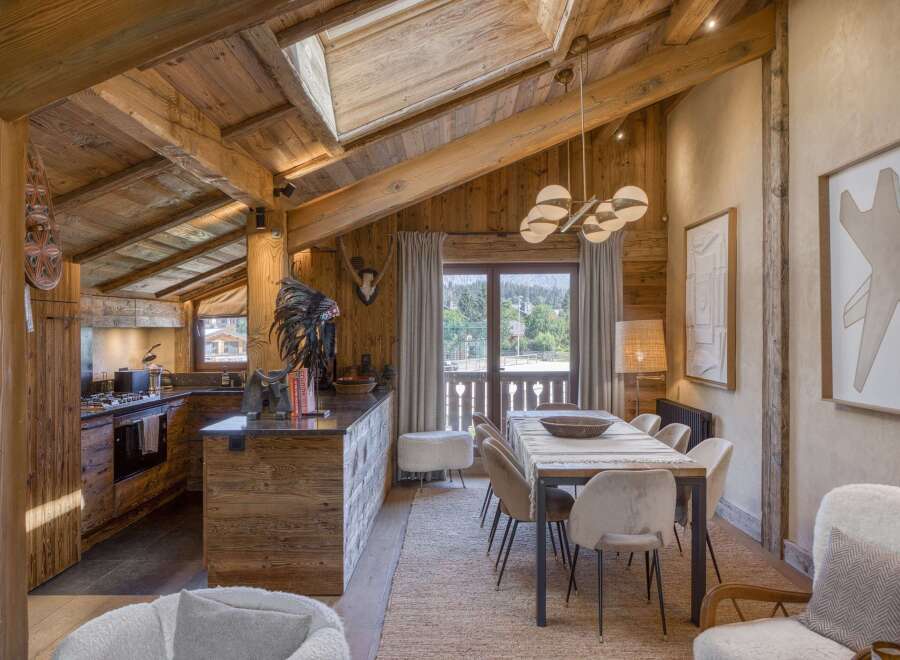 Experience rustic luxury in this stunning mountain chalet, featuring a spacious open-plan living area with exposed wooden beams and a vaulted ceiling.