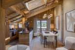 Experience rustic luxury in this stunning mountain chalet, featuring a spacious open-plan living area with exposed wooden beams and a vaulted ceiling.