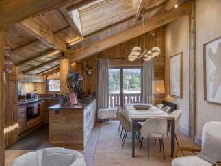 Experience rustic luxury in this stunning mountain chalet, featuring a spacious open-plan living area with exposed wooden beams and a vaulted ceiling.