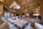 Experience rustic luxury in this stunning alpine dining and kitchen area, featuring a grand wooden-beamed ceiling and a large dining table perfect for gatherings.