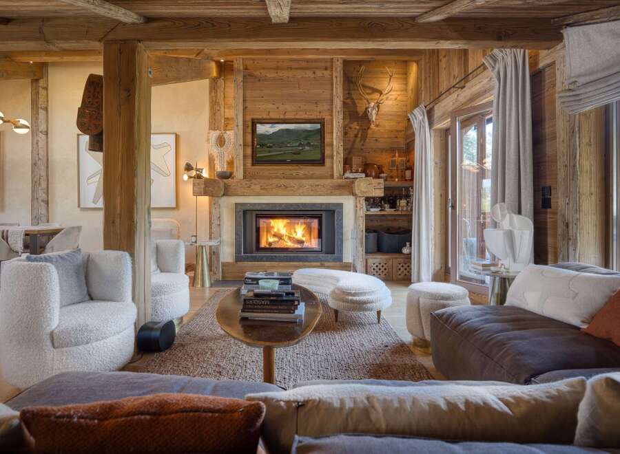 Experience rustic luxury in this stunning living room, featuring a grand fireplace with a stone surround and a mounted deer head.