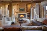 Experience rustic luxury in this stunning living room, featuring a grand fireplace with a stone surround and a mounted deer head.