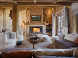 Experience rustic luxury in this stunning living room, featuring a grand fireplace with a stone surround and a mounted deer head.