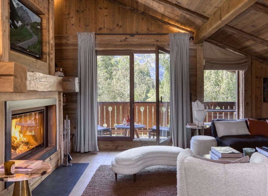 Experience rustic luxury in this charming living room, featuring a grand stone fireplace and exposed wooden beams.