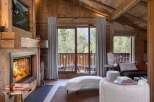 Experience rustic luxury in this charming living room, featuring a grand stone fireplace and exposed wooden beams.