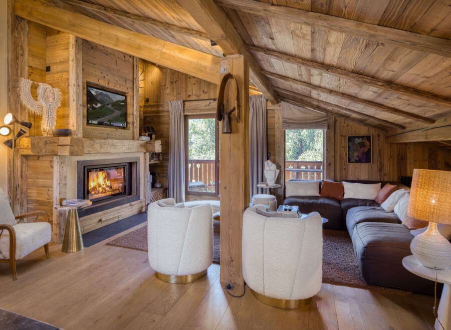 Experience rustic luxury in this stunning mountain chalet living room, featuring a roaring fireplace and exposed wooden beams.
