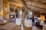 Experience rustic luxury in this stunning mountain chalet living room, featuring a roaring fireplace and exposed wooden beams.