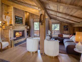 Experience rustic luxury in this stunning mountain chalet living room, featuring a roaring fireplace and exposed wooden beams.