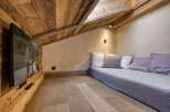 Experience cozy living in this charming attic room, featuring rustic wooden walls and ceiling, complemented by a comfortable daybed with plush pillows.