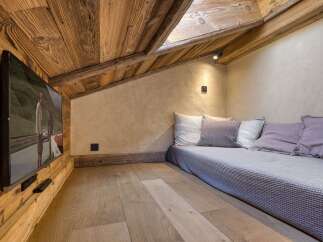 Experience cozy living in this charming attic room, featuring rustic wooden walls and ceiling, complemented by a comfortable daybed with plush pillows.