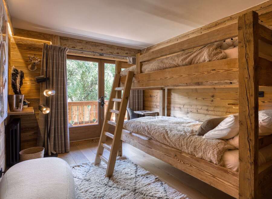 Experience rustic charm in this cozy bedroom featuring a wooden bunk bed and a balcony with a scenic view.