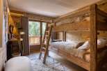 Experience rustic charm in this cozy bedroom featuring a wooden bunk bed and a balcony with a scenic view.