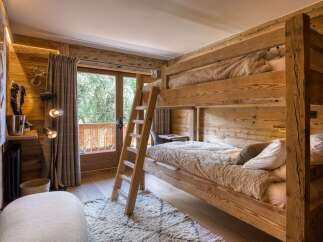 Experience rustic charm in this cozy bedroom featuring a wooden bunk bed and a balcony with a scenic view.