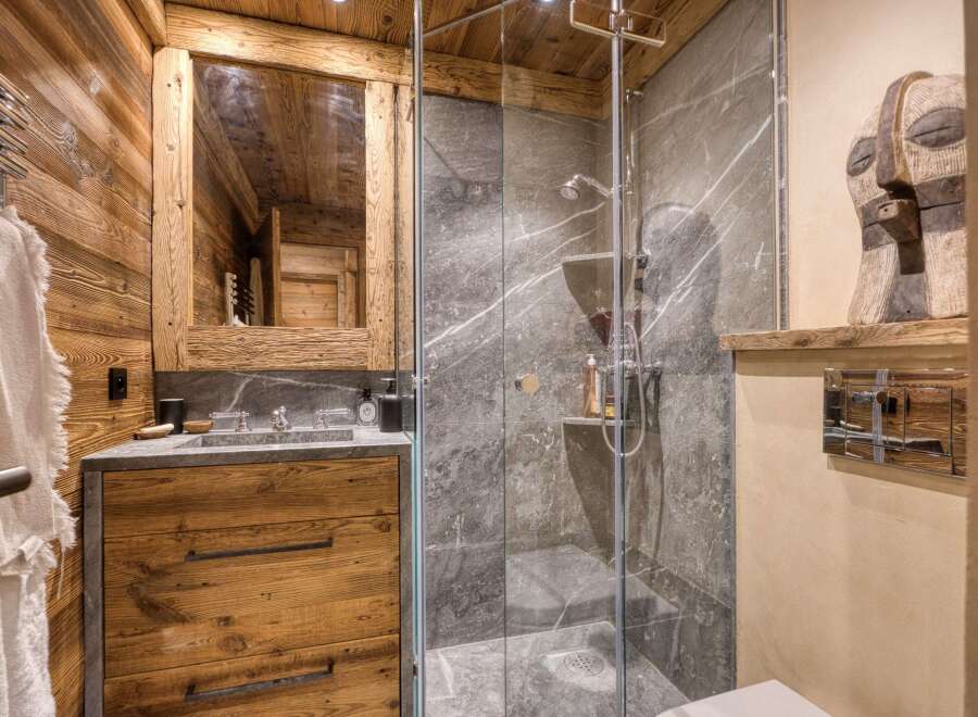 Experience rustic luxury in this charming bathroom, featuring warm wooden walls and a sleek stone vanity.