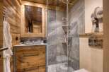 Experience rustic luxury in this charming bathroom, featuring warm wooden walls and a sleek stone vanity.