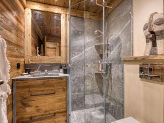 Experience rustic luxury in this charming bathroom, featuring warm wooden walls and a sleek stone vanity.