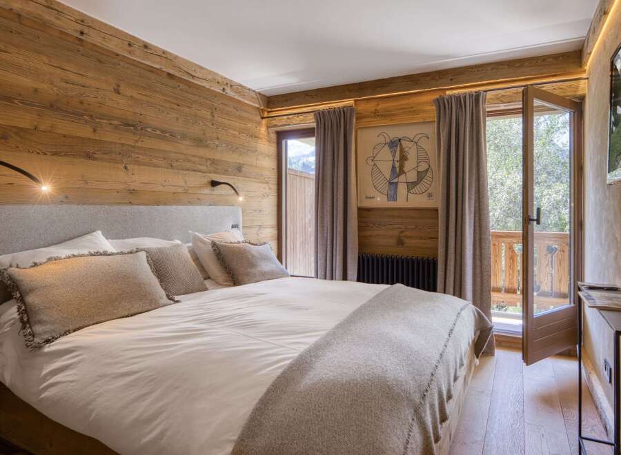 Experience rustic charm and modern comfort in this beautifully appointed bedroom, featuring warm wood paneling and a plush king-sized bed.