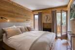 Experience rustic charm and modern comfort in this beautifully appointed bedroom, featuring warm wood paneling and a plush king-sized bed.