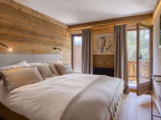 Experience rustic charm and modern comfort in this beautifully appointed bedroom, featuring warm wood paneling and a plush king-sized bed.