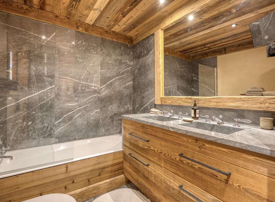 Experience rustic luxury in this stunning bathroom, featuring a deep soaking tub and a spacious double vanity with stone countertops.