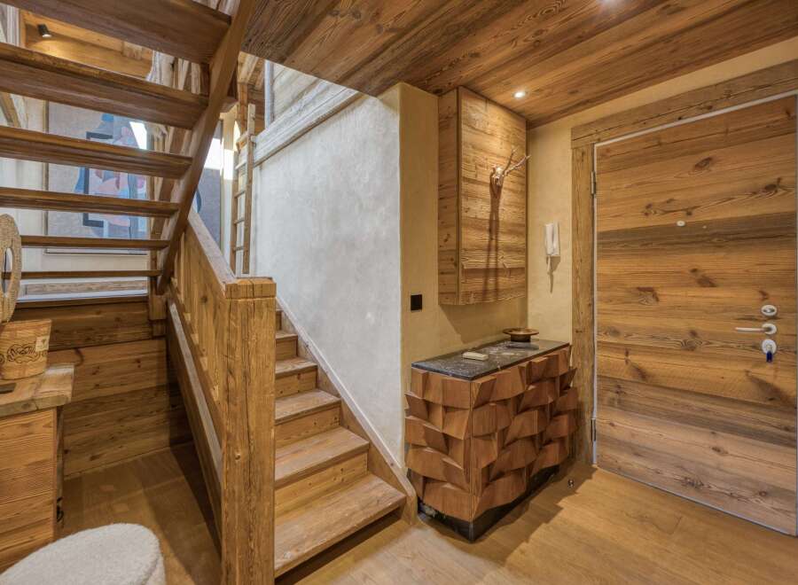 Experience rustic charm in this mountain chalet featuring a beautiful wooden staircase and a unique geometric cabinet.