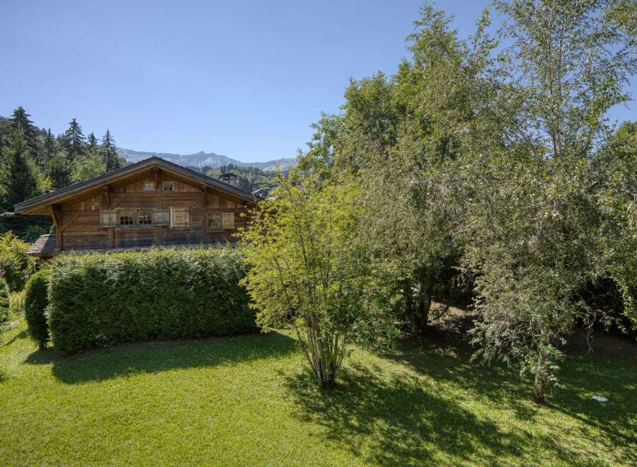 Nestled amidst lush greenery and mature trees, this charming wooden chalet offers a serene mountain retreat.