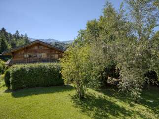 Nestled amidst lush greenery and mature trees, this charming wooden chalet offers a serene mountain retreat.