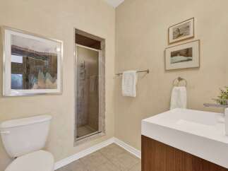 This bathroom features a modern white vanity with a sleek faucet and a built-in sink, complemented by a stylish soap dispenser and a decorative plant.