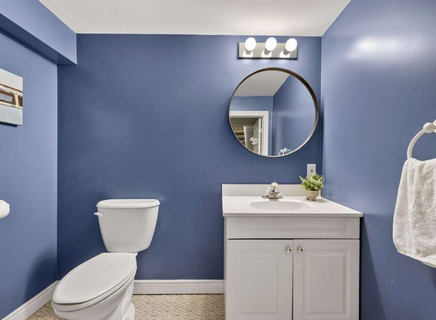 This charming bathroom features a sleek white vanity with a modern sink and a round mirror above.