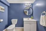 This charming bathroom features a sleek white vanity with a modern sink and a round mirror above.
