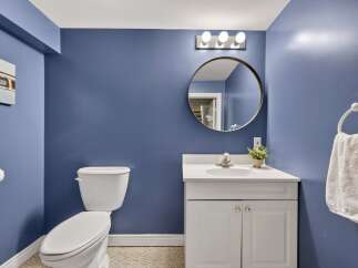 This charming bathroom features a sleek white vanity with a modern sink and a round mirror above.