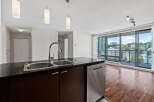 Experience modern living in this stunning condo featuring a sleek kitchen island with a double sink and stainless steel dishwasher.