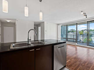 Experience modern living in this stunning condo featuring a sleek kitchen island with a double sink and stainless steel dishwasher.