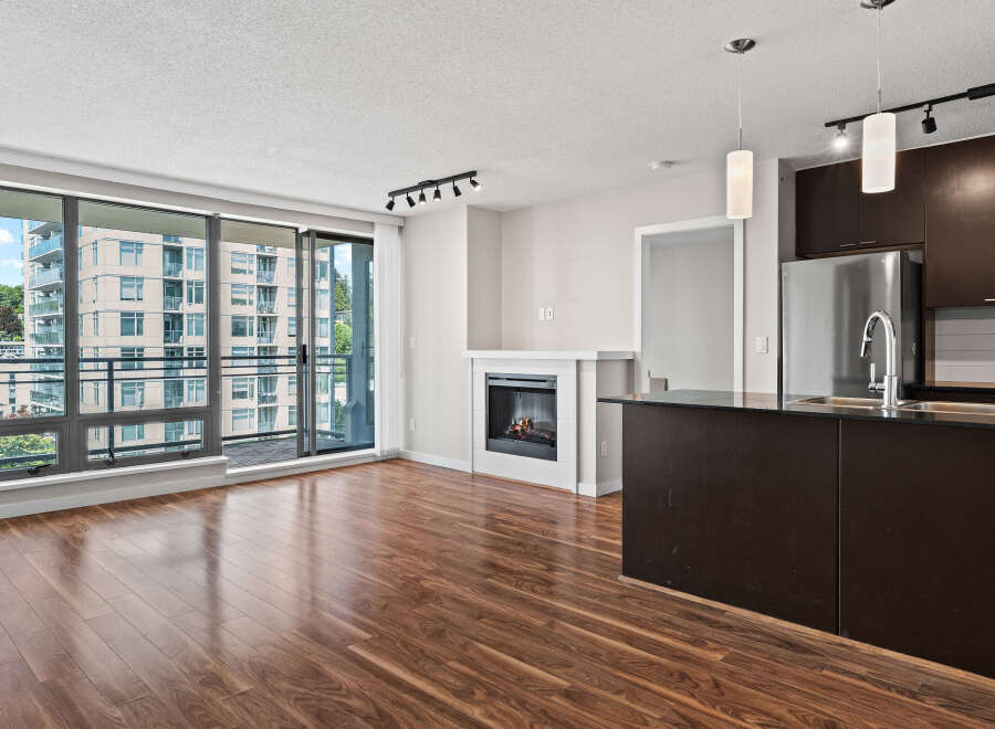Experience modern living in this spacious condo featuring a cozy fireplace and a sleek, dark-wood kitchen island with a stainless steel sink.
