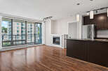 Experience modern living in this spacious condo featuring a cozy fireplace and a sleek, dark-wood kitchen island with a stainless steel sink.