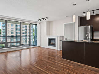 Experience modern living in this spacious condo featuring a cozy fireplace and a sleek, dark-wood kitchen island with a stainless steel sink.