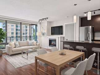 Experience modern living in this stunning condo featuring a spacious open-concept living area with a cozy fireplace and large windows.