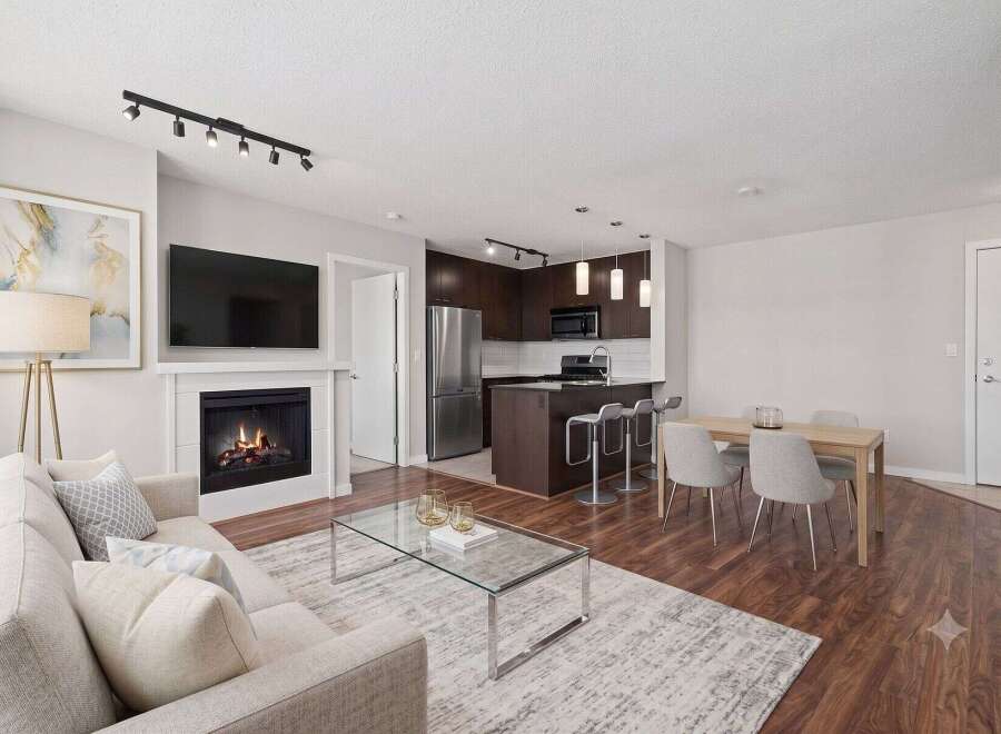 Experience modern living in this open-concept condo featuring a cozy fireplace and a sleek kitchen with a breakfast bar.