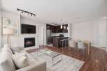 Experience modern living in this open-concept condo featuring a cozy fireplace and a sleek kitchen with a breakfast bar.