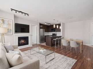 Experience modern living in this open-concept condo featuring a cozy fireplace and a sleek kitchen with a breakfast bar.