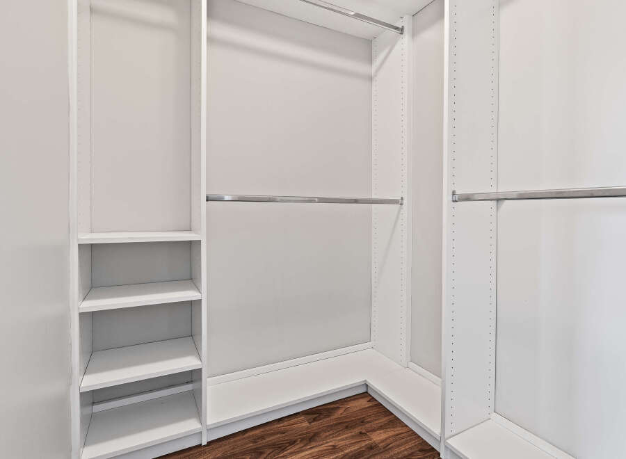 This spacious walk-in closet features a clean, modern design with ample shelving and multiple hanging rods.
