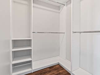 This spacious walk-in closet features a clean, modern design with ample shelving and multiple hanging rods.