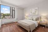 Experience modern urban living in this beautifully appointed bedroom, featuring a large window with stunning city views.