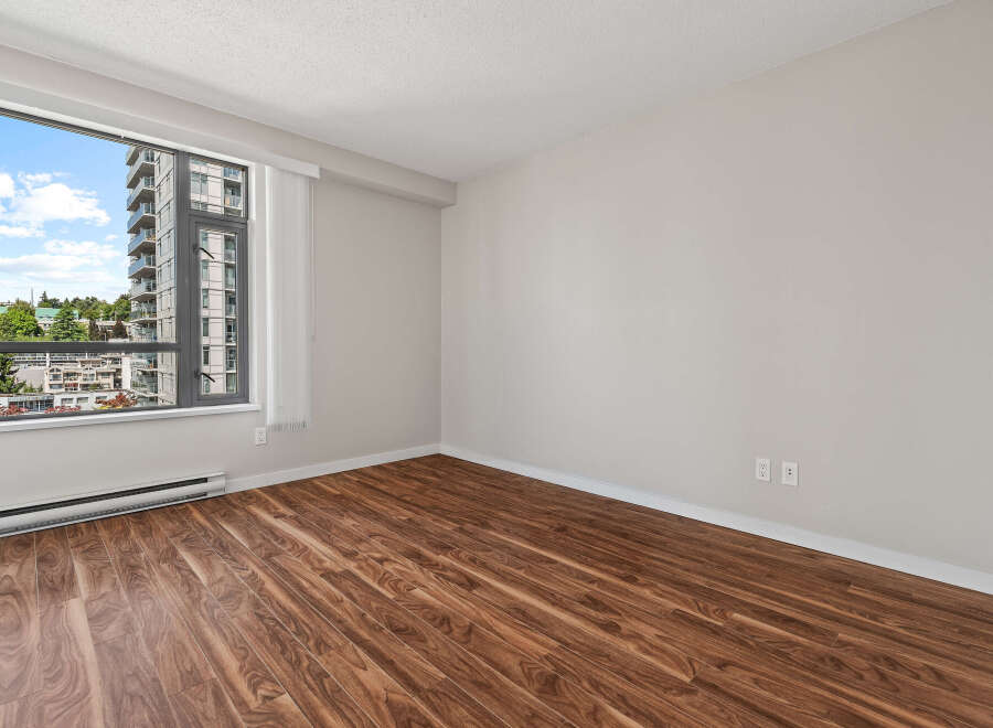 Experience modern living in this spacious room featuring beautiful hardwood floors and a large window with city views.