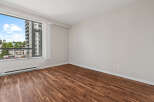 Experience modern living in this spacious room featuring beautiful hardwood floors and a large window with city views.