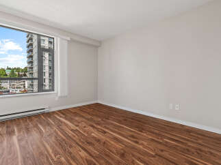 Experience modern living in this spacious room featuring beautiful hardwood floors and a large window with city views.