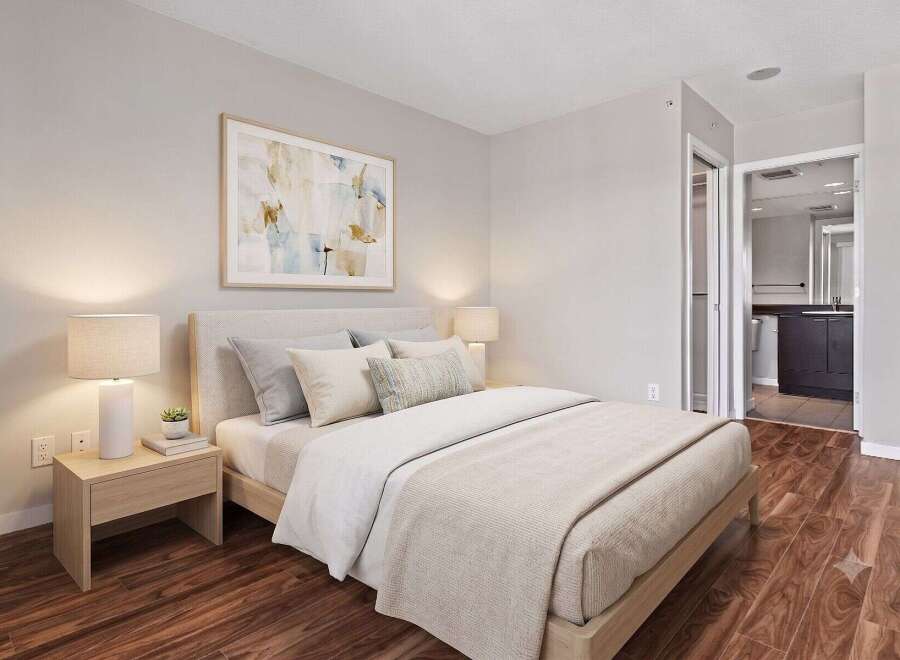 Experience comfort and style in this beautifully appointed bedroom, featuring a plush bed, elegant nightstands with lamps, and a captivating piece of wall art.