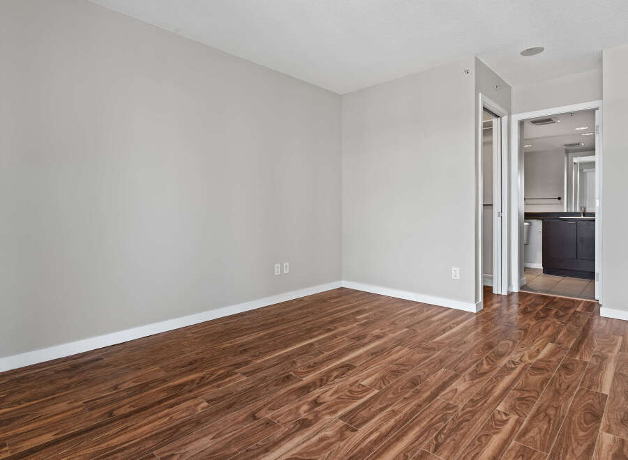 Experience modern living in this spacious room featuring elegant hardwood-style flooring and neutral gray walls.