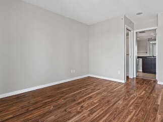 Experience modern living in this spacious room featuring elegant hardwood-style flooring and neutral gray walls.