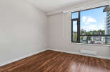 Experience modern living in this spacious room featuring elegant hardwood floors and a large window with stunning city views.